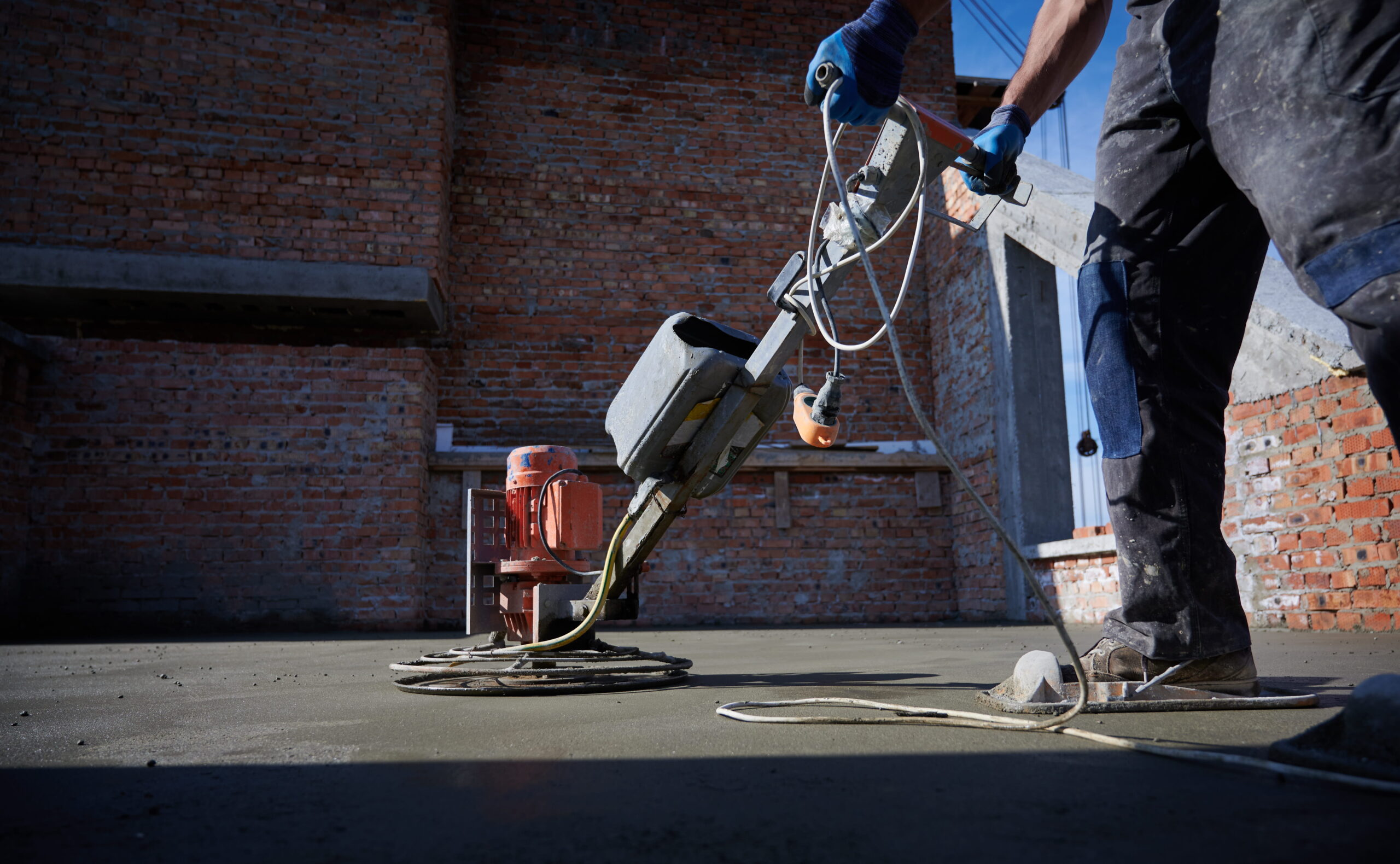 Crew finishing an outdoor concrete slab with a power trowel